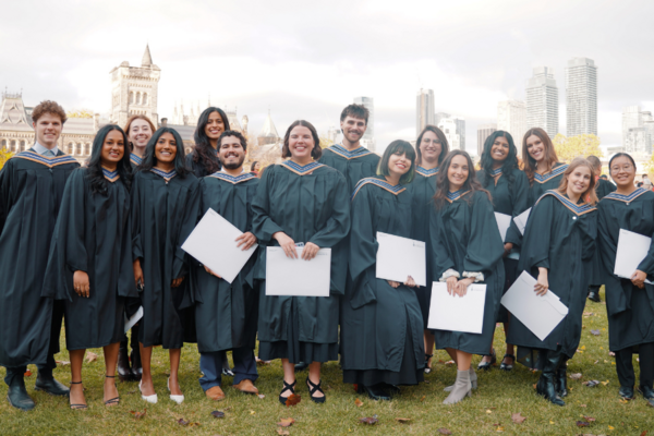 A group of people in convocation gowns smiling at the camera